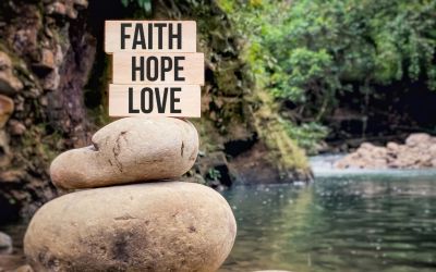 Photo of a sign on the shore of a lake with the words Faith, Hope, Love, to illustrate the article Hope and Faith in Action.
